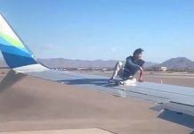 விமானத்தின் இறக்கையின் மேல் ஏறிய மனிதன்